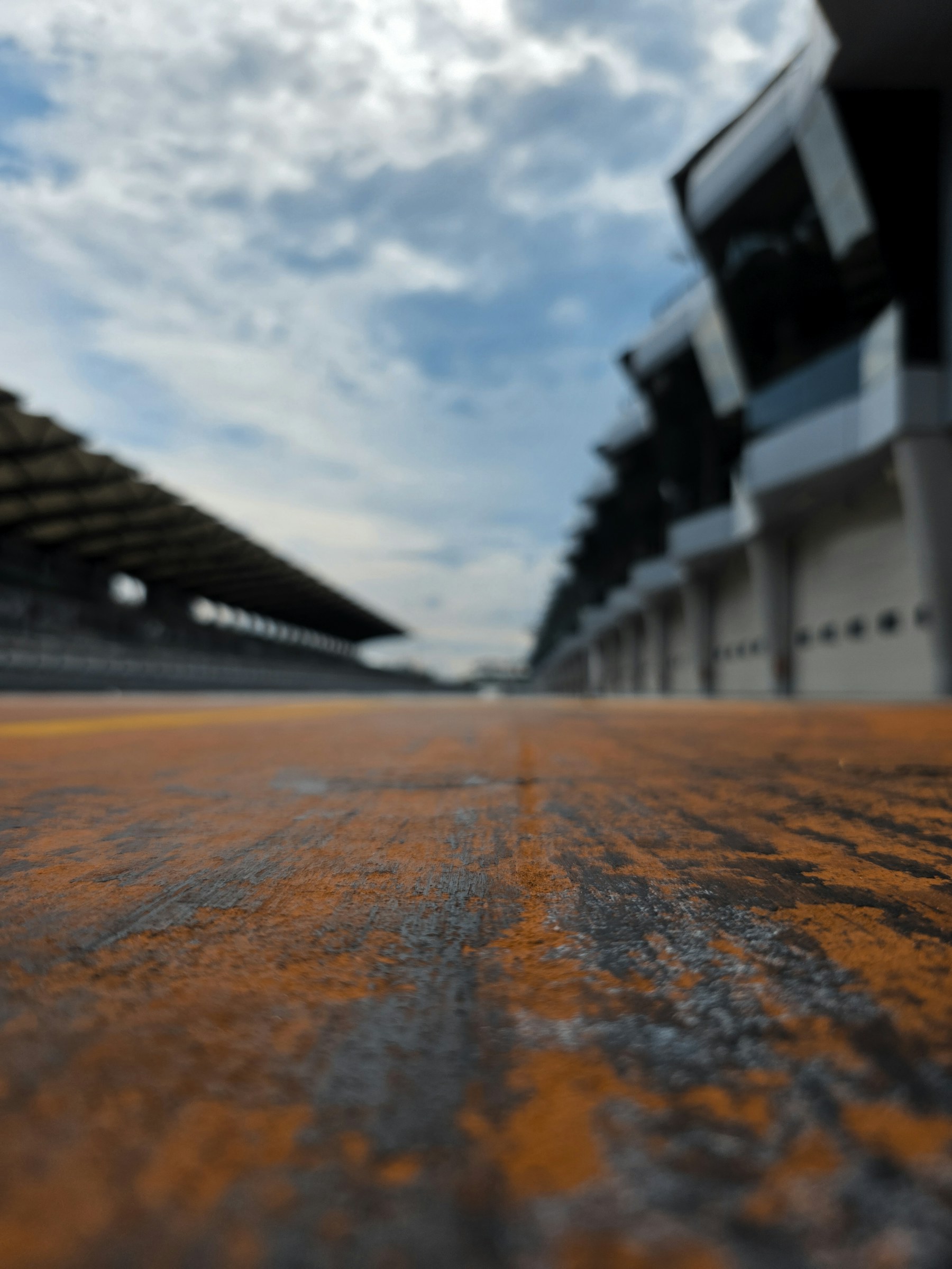 Low-angle view along Sepang pit lane beneath a dramatic cloudy sky